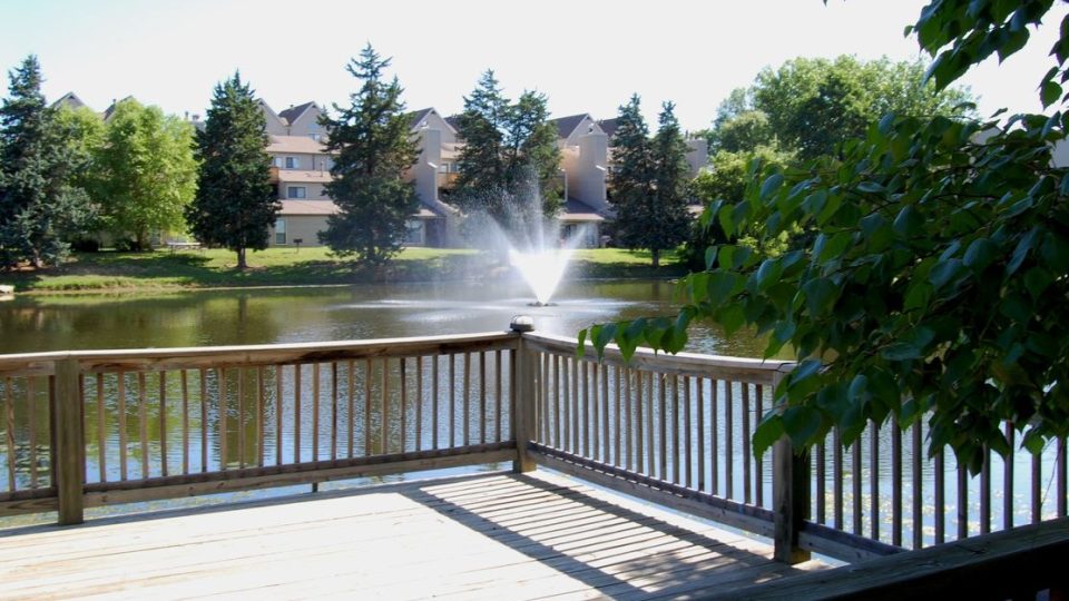a wooden deck with a fountain and a pond at The Lakeside Village