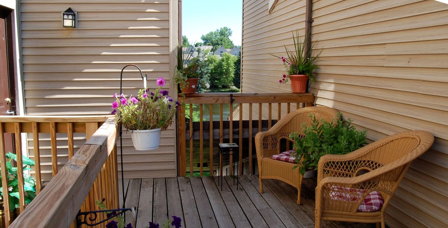 a deck with two wicker chairs and a potted plant at The Lakeside Village