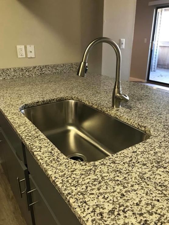 a kitchen with granite counter tops and stainless steel sink at The Lakeside Village